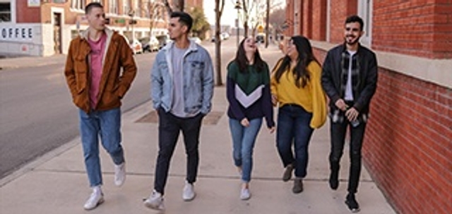 photo of five teenagers walking together on sidewalk
