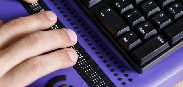 Person's hands on a Braille keyboard